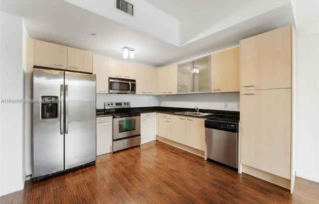 a kitchen with granite countertop a refrigerator and a stove top oven