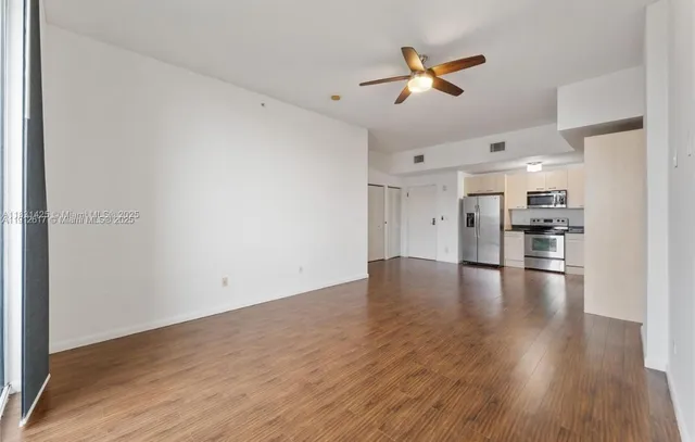 a view of empty room with wooden floor and ceiling fan