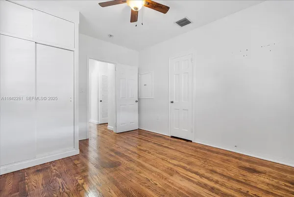 an empty room with wooden floor cabinet and windows