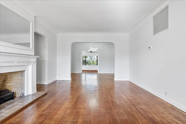 an empty room with wooden floor fireplace and windows