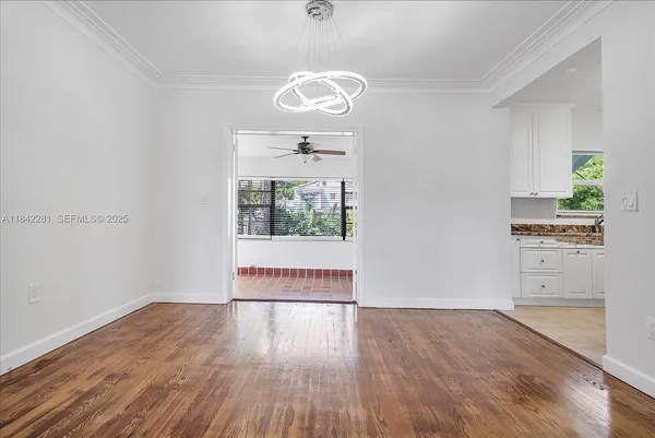 an empty room with wooden floor cabinet and windows
