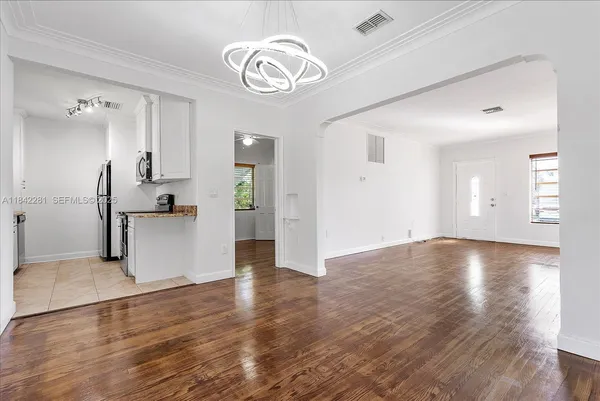 a kitchen with a stove a sink and white cabinets with wooden floor