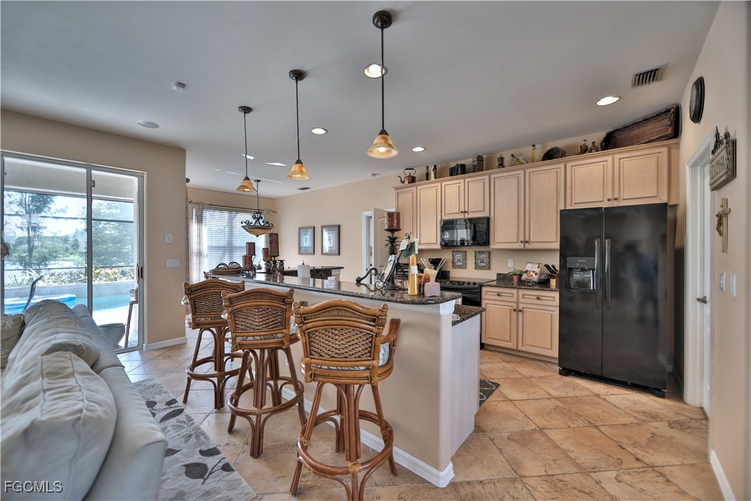 15022 Balmoral Loop Fort Myers, FL 33919 - Photo 24 of 27 a kitchen with stainless steel appliances granite countertop a refrigerator a stove top oven a sink dishwasher a dining table and chairs with wooden floor