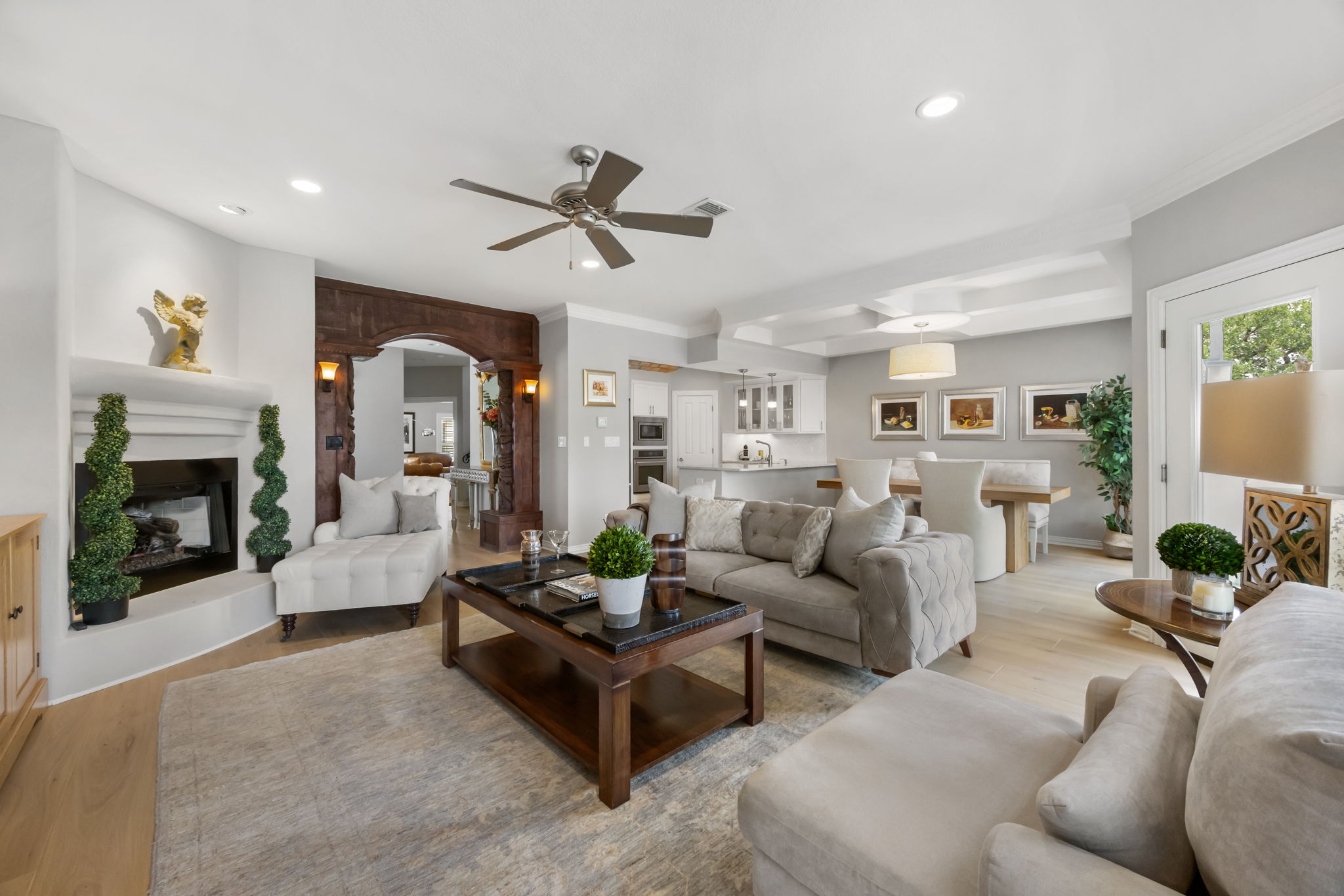 1910 Rue De St Tropez, Unit 6 Austin, TX 78746 - Photo 7 of 37 A refined living area unfolds, featuring a prominent fireplace, warm hardwood floors, and graceful arched entryways.