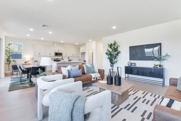 a living room with furniture and a glass table with kitchen view