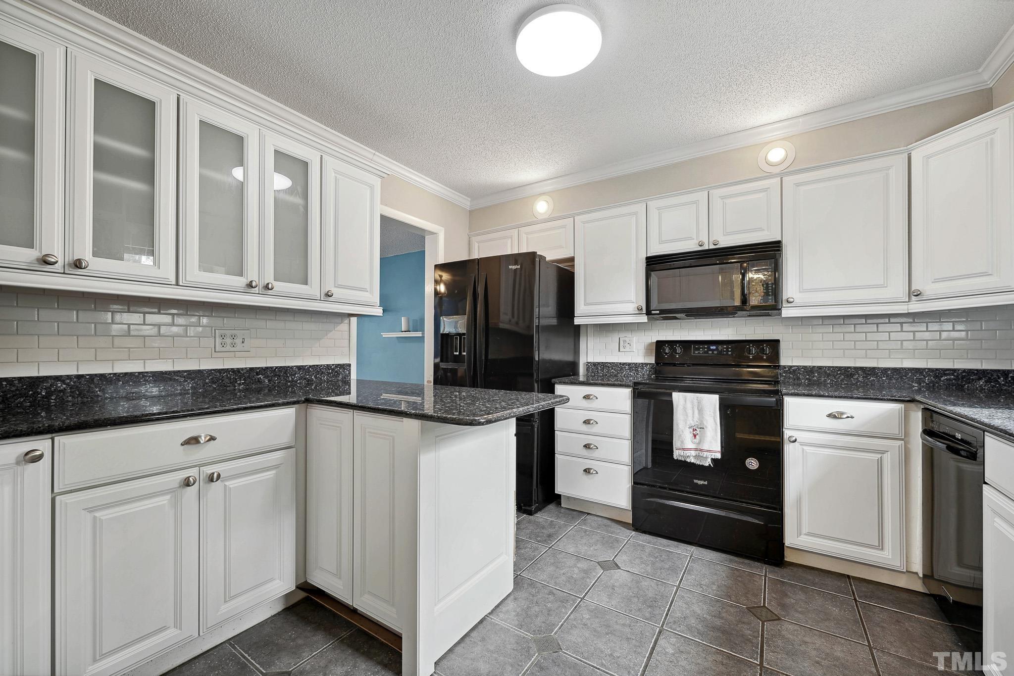 5809 Nottoway Court, Unit B Raleigh, NC 27609 - Photo 10 of 21 a kitchen with white cabinets and black appliances