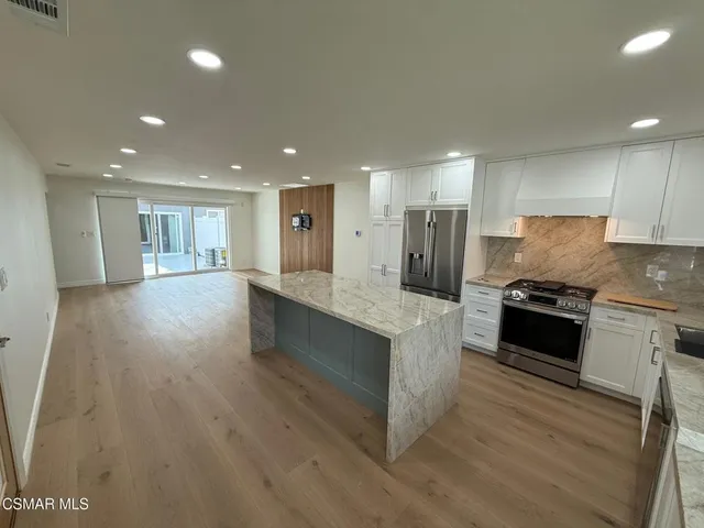 a large kitchen with stainless steel appliances granite countertop a large counter top and a stove top oven