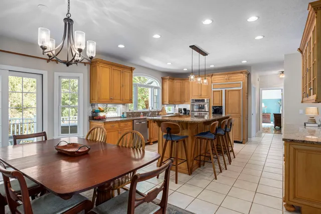 a kitchen with stainless steel appliances a table chairs sink refrigerator and cabinets