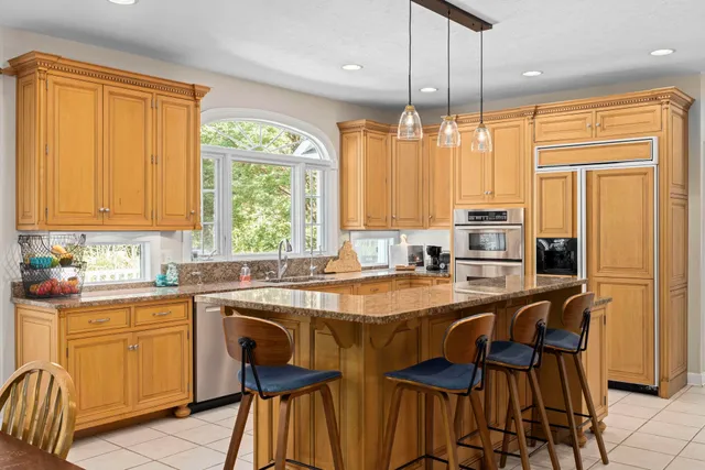 a kitchen with granite countertop a stove a sink a dining table and chairs