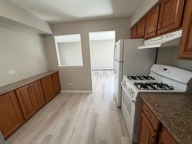 a kitchen with a refrigerator a stove and wooden floor