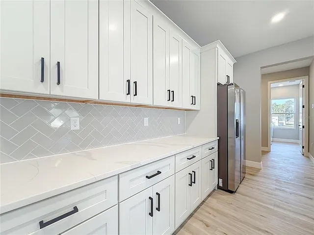 a kitchen with stainless steel appliances granite countertop a refrigerator sink and white cabinets