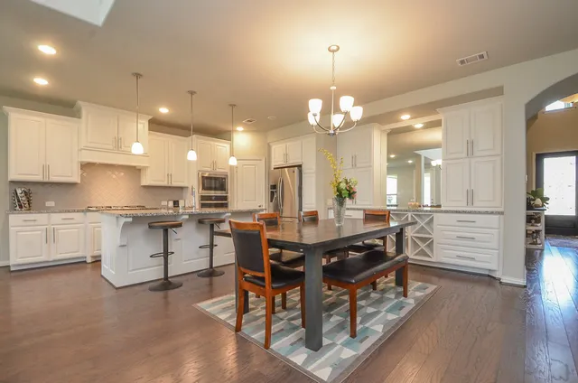 a kitchen with stainless steel appliances kitchen island granite countertop a table chairs and a refrigerator