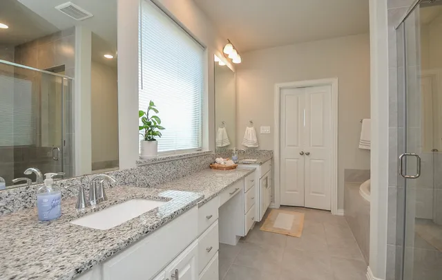a bathroom with a granite countertop double vanity sink and a mirror