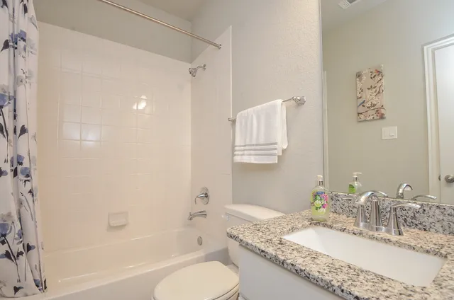 a bathroom with a granite countertop sink toilet and shower