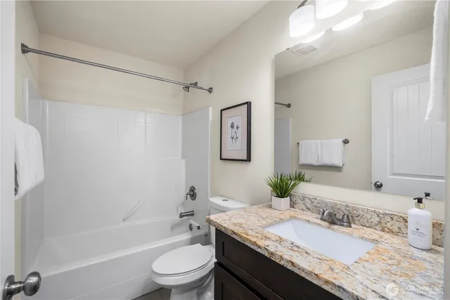 a bathroom with a granite countertop bathtub sink vanity mirror and toilet