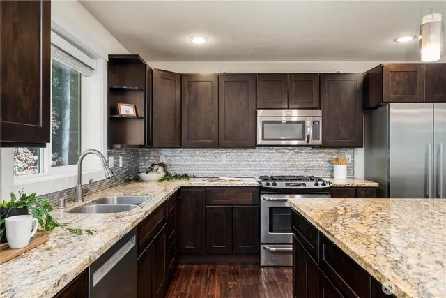 a kitchen with stainless steel appliances granite countertop a sink stove and refrigerator