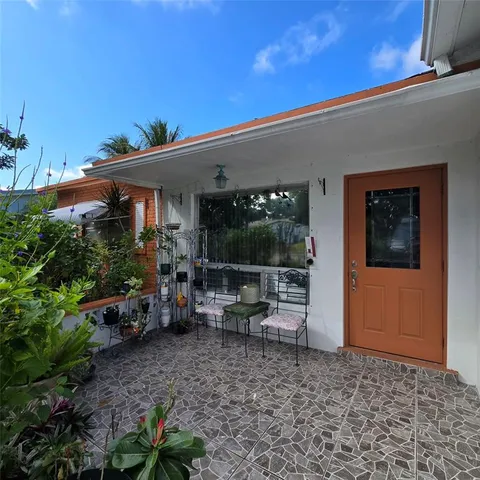 a view of a patio with table and chairs potted plants and floor to ceiling window