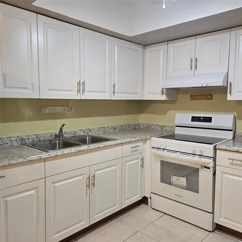 a kitchen with granite countertop white cabinets and white appliances