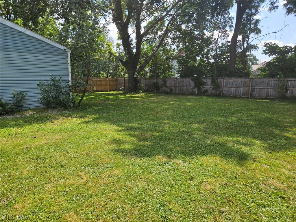 753 West River Road North Elyria, OH 44035 - Photo 28 of 28 Expansive backyard featuring a large grassy area, mature trees, and a full perimeter wood fence