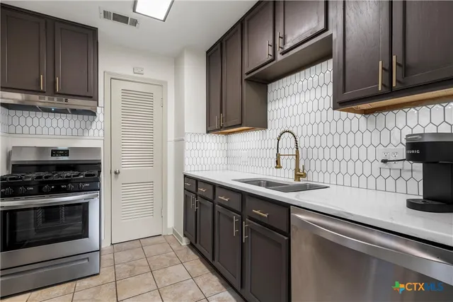a kitchen with stainless steel appliances granite countertop a sink stove and cabinets