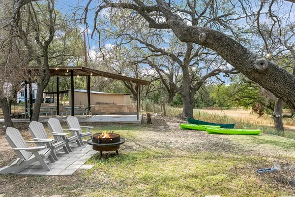 a view of a backyard with table and chairs potted plants and large tree