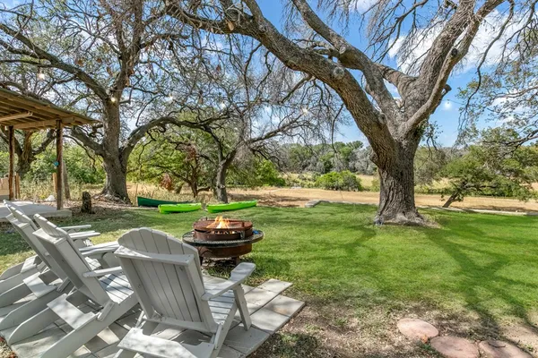 a view of a backyard with table and chairs and a large tree