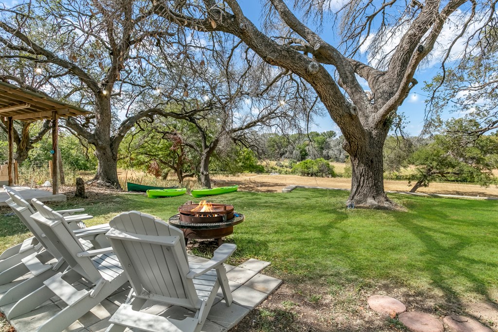 229 Ranch Road 1 Stonewall, TX 78671 - Photo 4 of 25 a view of a backyard with table and chairs and a large tree