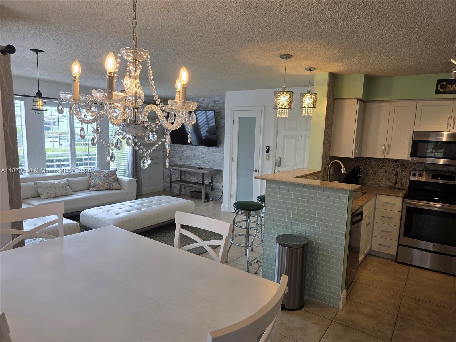 1365 Crystal Way, Unit G Delray Beach, FL 33444 - Photo 6 of 30 a living room with furniture a fireplace and a chandelier