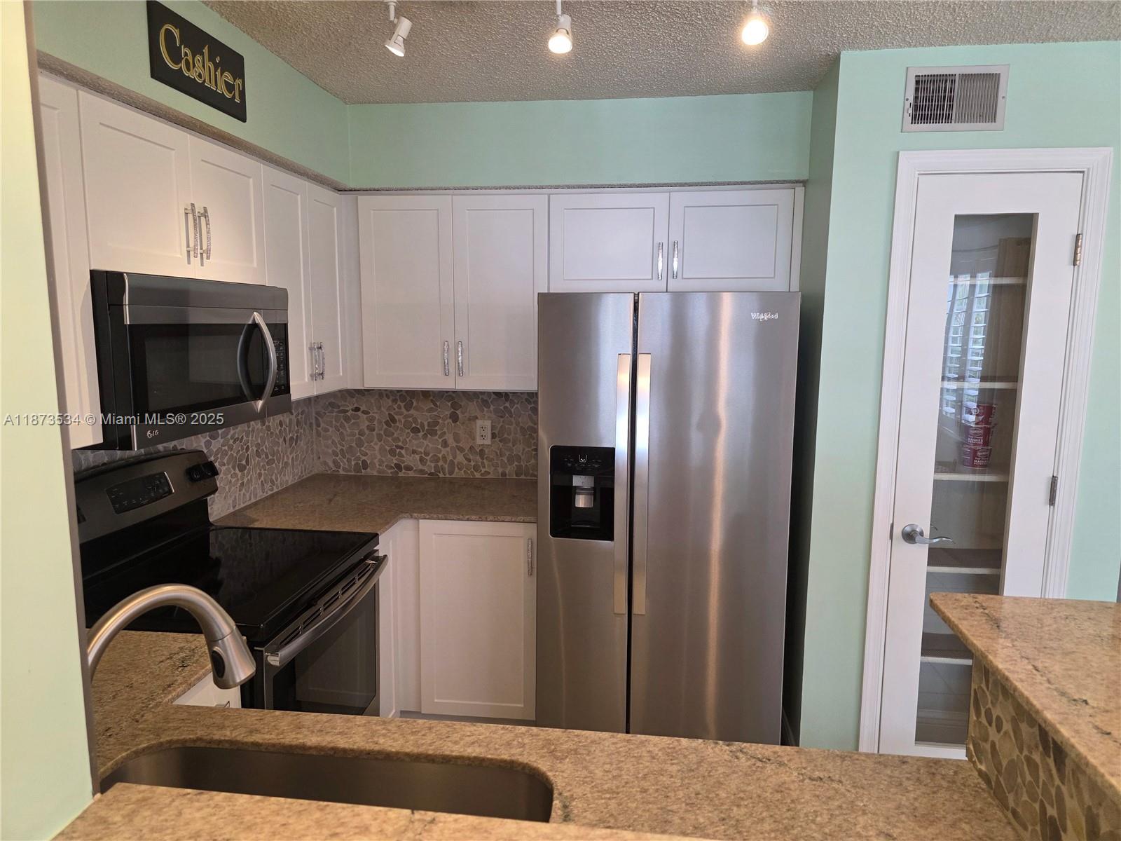1365 Crystal Way, Unit G Delray Beach, FL 33444 - Photo 8 of 30 a kitchen with granite countertop a refrigerator and a sink