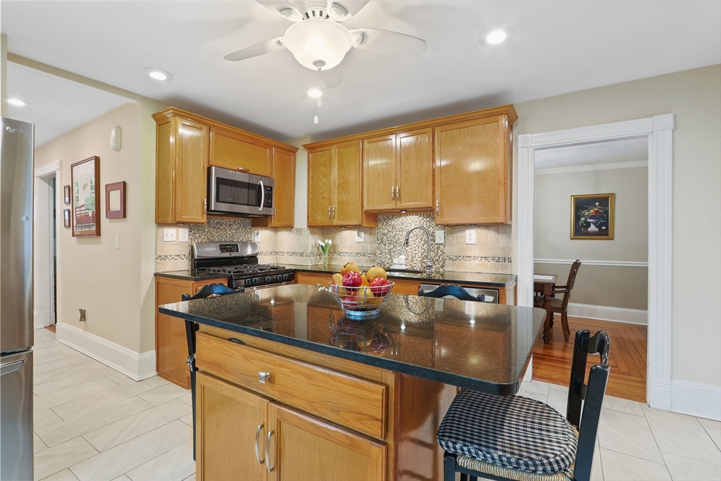42 Partridge Street Boston, MA 02132 - Photo 2 of 33 a kitchen with stainless steel appliances granite countertop a stove a refrigerator a sink a dining table and chairs