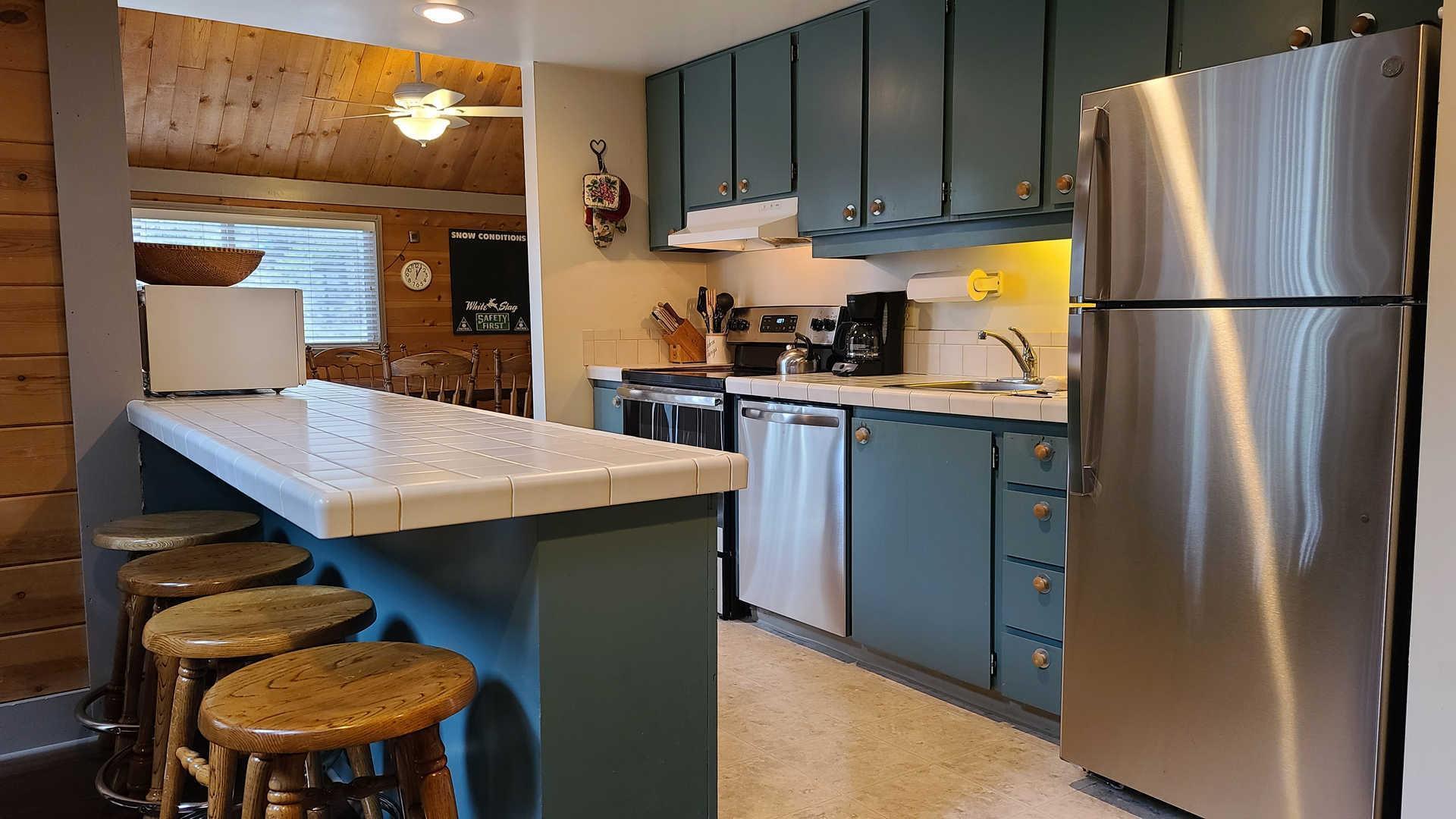 57397 Overlook Road Sunriver, OR 97707 - Photo 3 of 23 Eye-catching blue cabinets pop against classic white tile countertops and stainless Steele appliances.
