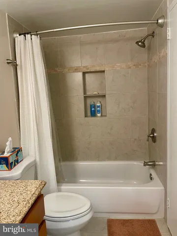 a bathroom with a granite countertop bathtub shower and toilet