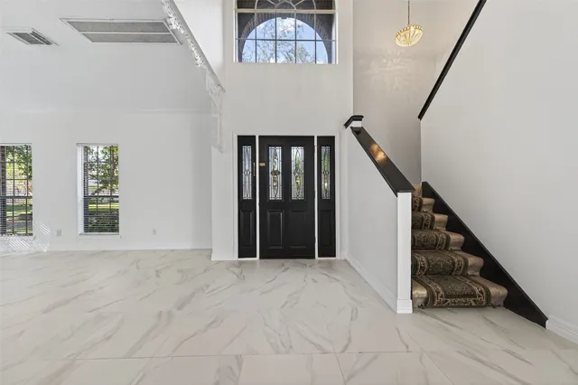 a view of an empty room with a window and a kitchen