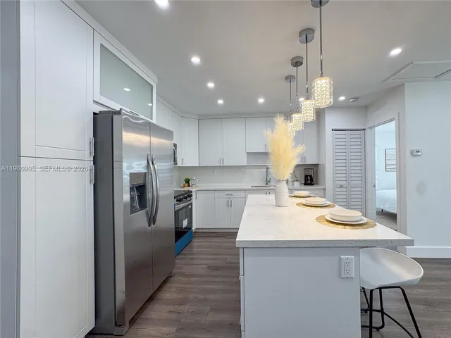 a kitchen with kitchen island white cabinets and stainless steel appliances