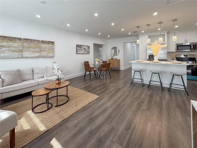 a living room with furniture and kitchen view with wooden floor