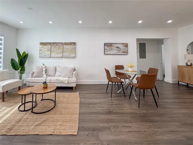 a living room with furniture a wooden floor and a potted plant