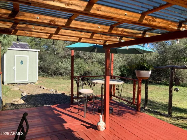 a view of a patio with table and chairs under an umbrella with a small yard