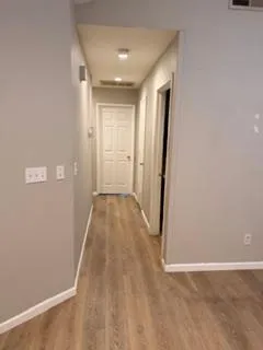 a view of a hallway with wooden floor and a bathroom