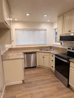 a kitchen with a stove white cabinets counter top space and a sink