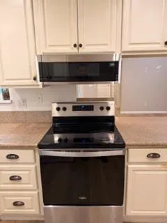 a kitchen with granite countertop white cabinets and black appliances