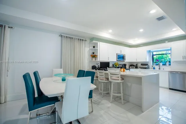 a room with stainless steel appliances kitchen island a table chairs in it