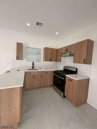 a large kitchen with stainless steel appliances a sink a stove a microwave a counter top and a refrigerator