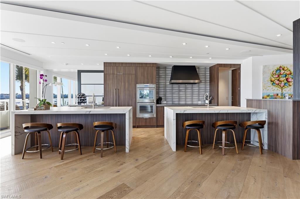 909 10th Street South, Unit 201 Naples, FL 34102 - Photo 2 of 42 Two tone kitchen with a breakfast bar area, light stone counters, modern cabinets, double oven, and recessed lighting