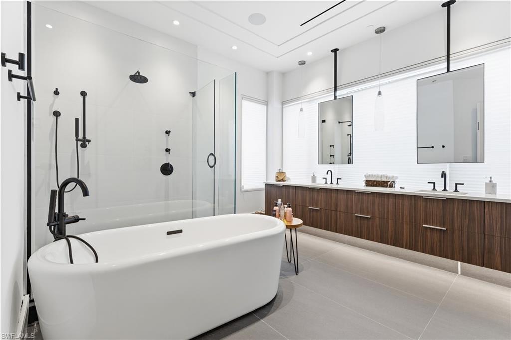 909 10th Street South, Unit 201 Naples, FL 34102 - Photo 33 of 42 Bathroom featuring double vanity, a freestanding bath, walk in shower, and light tile patterned flooring