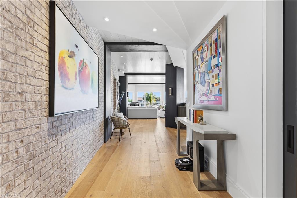 909 10th Street South, Unit 201 Naples, FL 34102 - Photo 41 of 42 Hall featuring brick wall, light wood finished floors, recessed lighting, and an accent wall