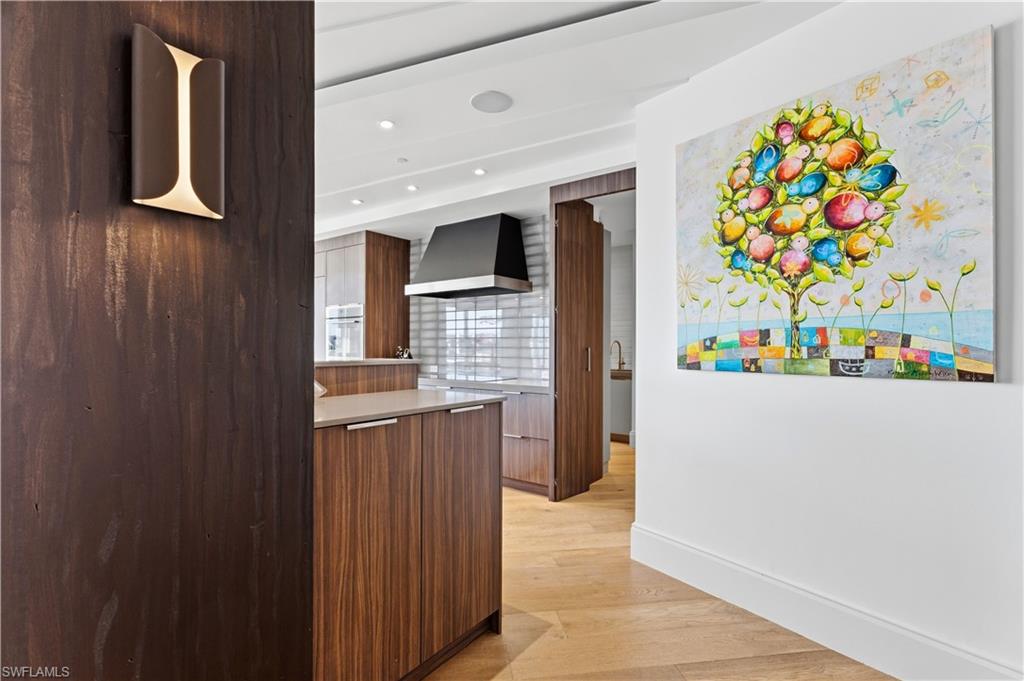 909 10th Street South, Unit 201 Naples, FL 34102 - Photo 42 of 42 Kitchen with modern cabinets, light wood-type flooring, recessed lighting, light stone countertops, and white oven