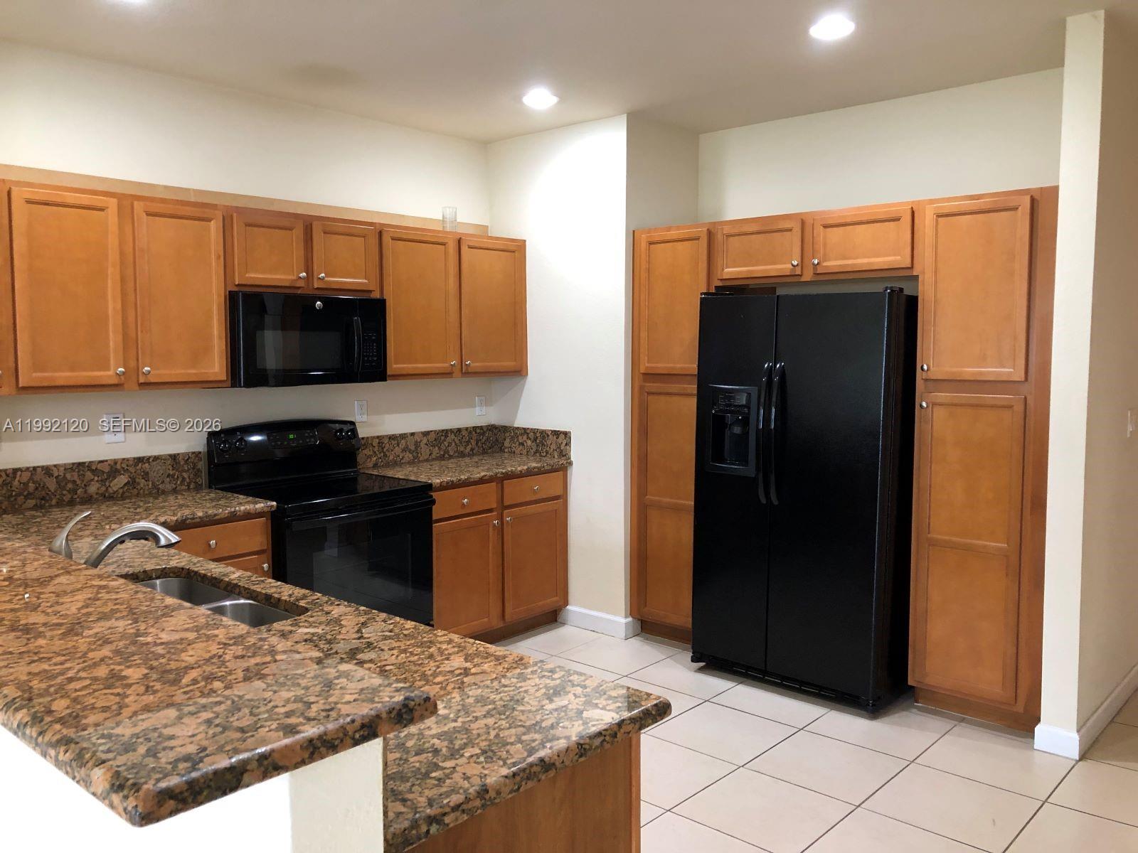 17000 Southwest 90th Terrace Miami, FL 33196 - Photo 31 of 56 a kitchen with granite countertop a refrigerator and a stove top oven
