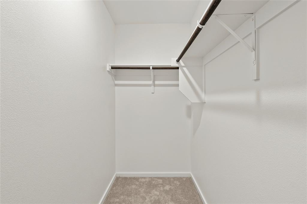 1138 Barbary Flds Street Forney, TX 75126 - Photo 15 of 25 Walk-in closet featuring light grey carpet flooring, white painted walls, and built-in shelving with hanging rods