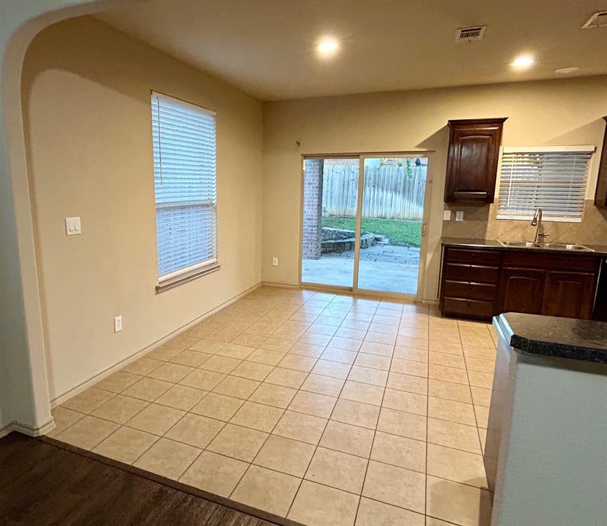 3105 Pecan Tree Drive Denton, TX 76210 - Photo 11 of 25 Kitchen with dark brown cabinetry, light tile patterned flooring, arched walkways, recessed lighting, and dark stone countertops