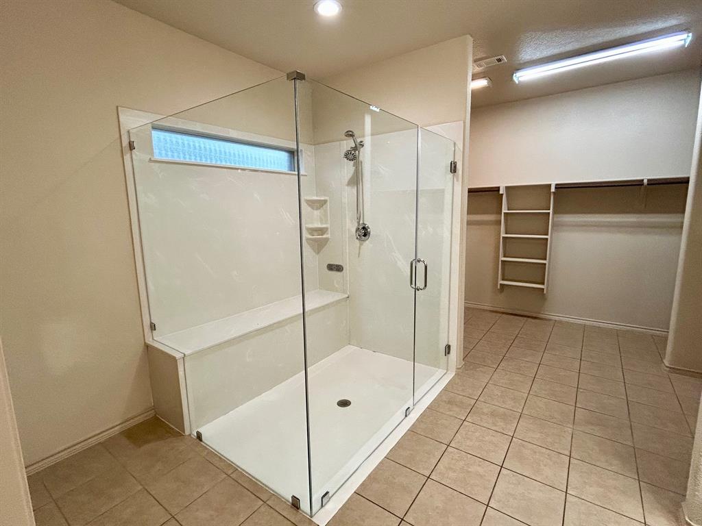 3105 Pecan Tree Drive Denton, TX 76210 - Photo 16 of 25 Full bathroom featuring a walk in closet, light tile patterned floors, and a shower stall